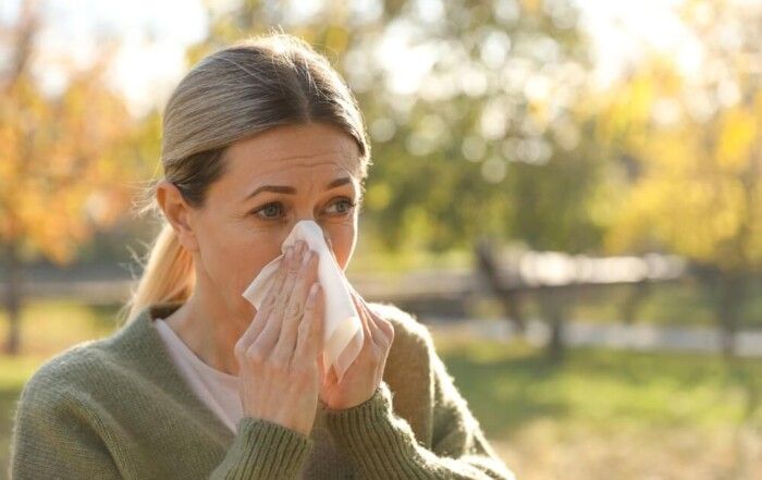 Mujer con congestión nasal debido al cambio de estación y a problemas respiratorios estacionales.