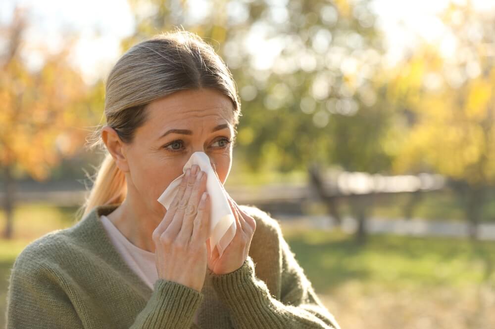 Mujer con congestión nasal debido al cambio de estación y a problemas respiratorios estacionales.